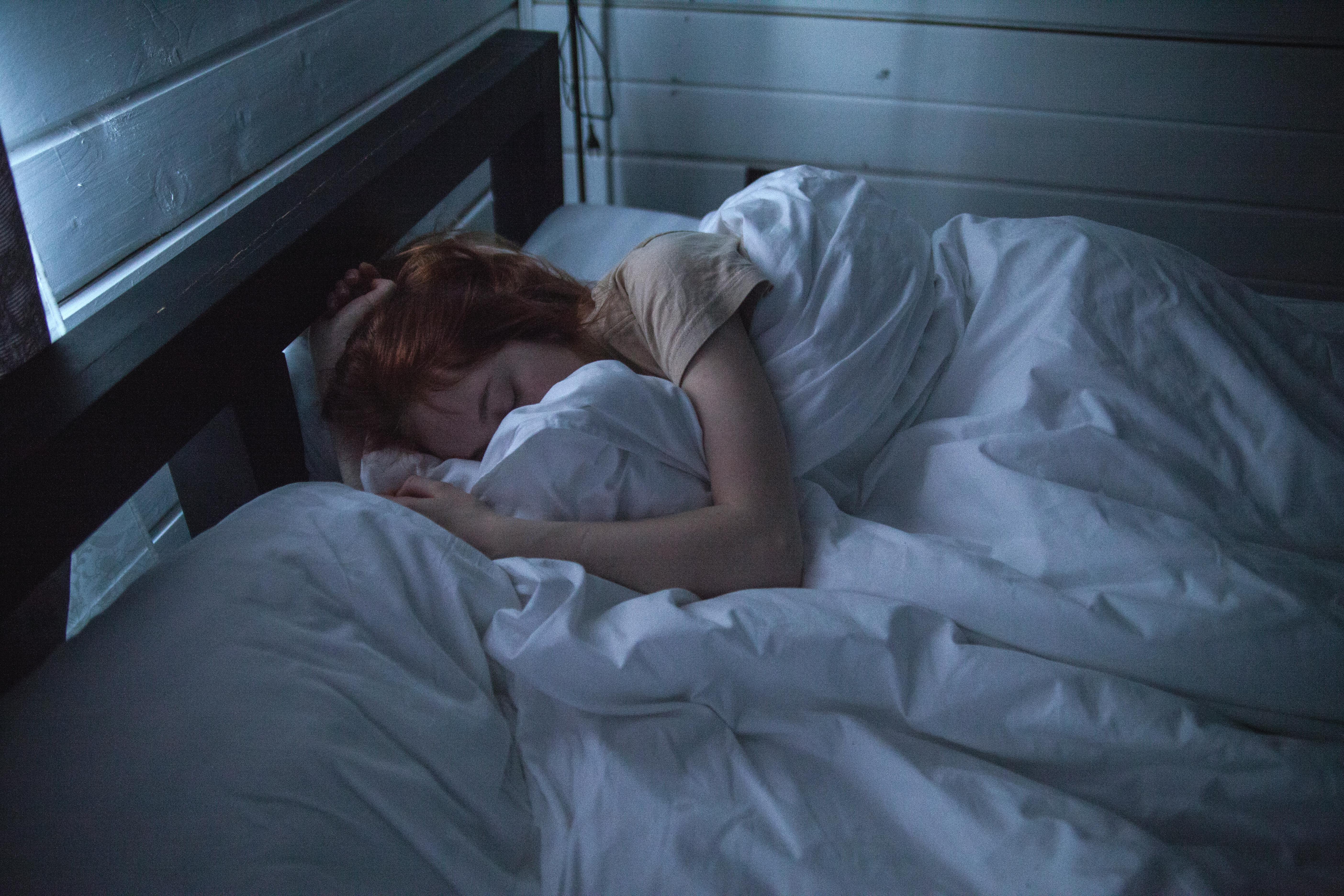 woman sleeping under a blanket in a dark room